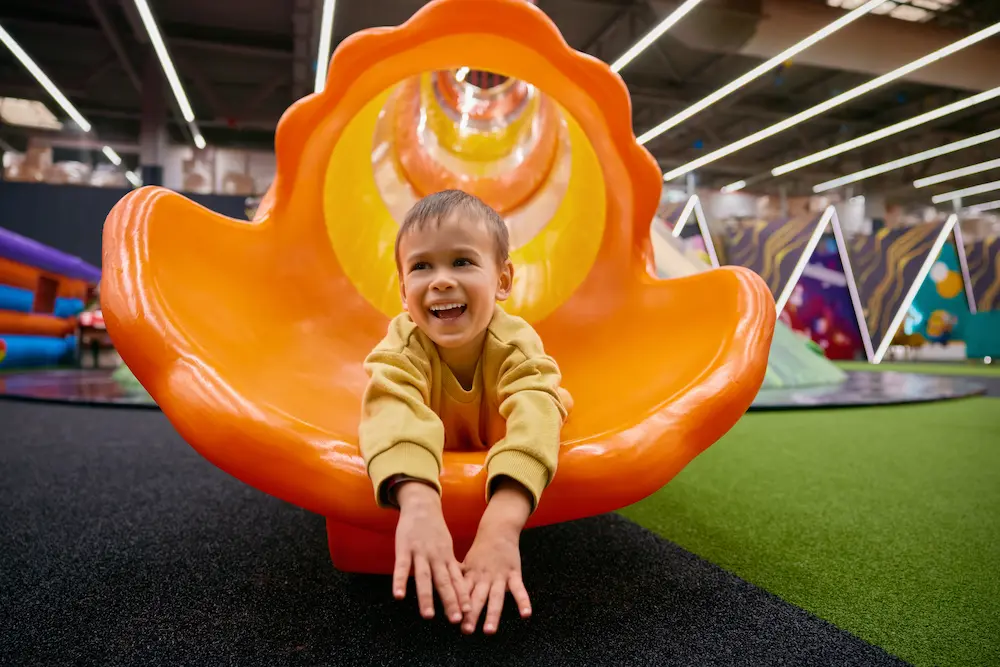 Playground interno, bambino sullo scivolo